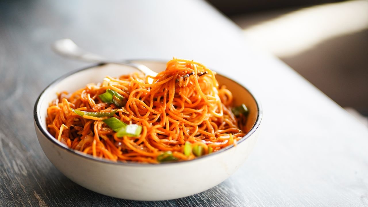 A close-up of a vibrant spaghetti dish with green peppers in a bowl.