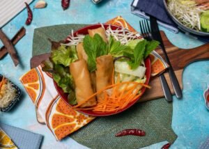 Colorful vegan spring rolls and fresh salad on a vibrant table setting.